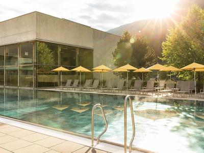 Moderner Hotelpool mit gelben Sonnenschirmen und Liegstühlen in der Abendsonne.