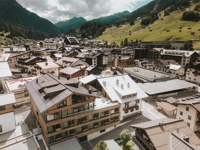 Blick auf ein Bergdorf mit traditionellen Gebäuden und grünen Berghängen im Hintergrund.