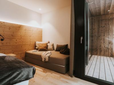 Modernes Hotelzimmer mit Holzakzenten, gemütlicher Sitzecke und Zugang zu einer Sauna.