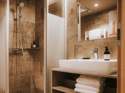 Modernes Badezimmer mit begehbarer Dusche, Waschbecken und Handtüchern in einem Hotelzimmer.