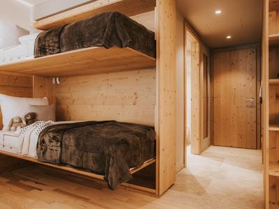 Modern eingerichteter Schlafraum mit Etagenbetten aus hellem Holz und warmer Beleuchtung.