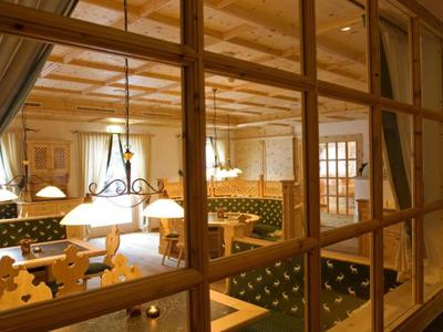 Gemütlicher Hotel-Speiseraum mit Holzmöbeln und grünen Polstern, warm beleuchtet.