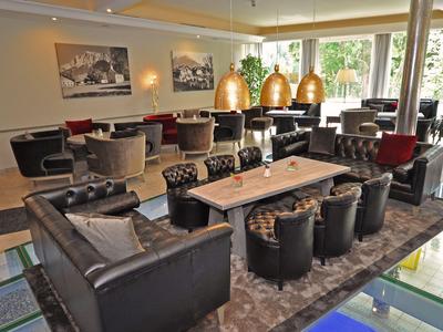 Moderne Hotellounge mit bequemen Ledersesseln und großen Fenstern, die viel Tageslicht bieten.