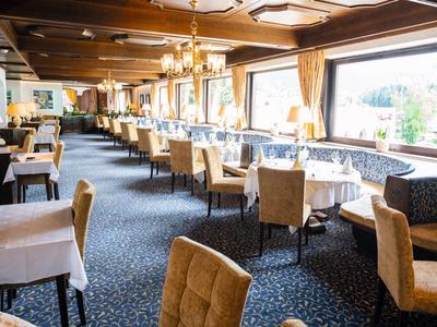 Großer, eleganter Speisesaal mit weißen gedeckten Tischen, bequemen Sesseln und warmem Licht.