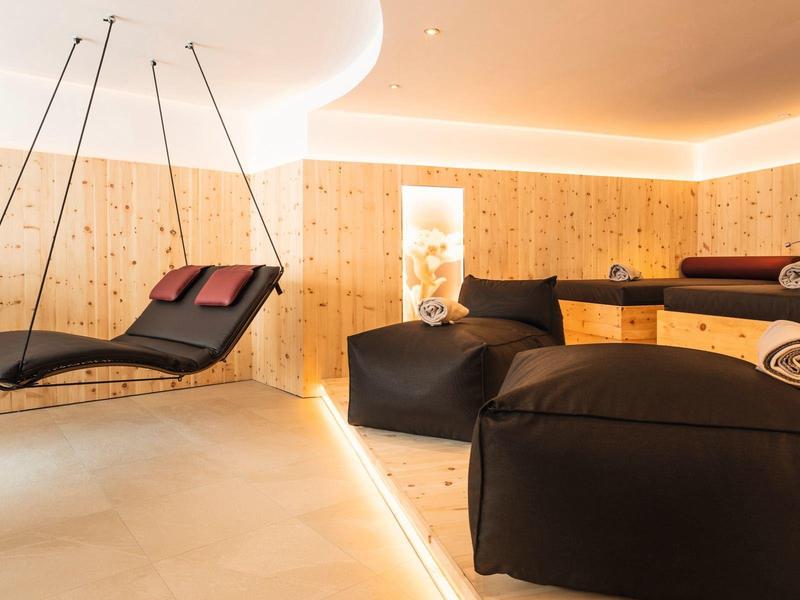 Moderner Wellnessraum mit Holzvertäfelung, zwei schwarzen Liegen und sanfter, indirekter Beleuchtung.
