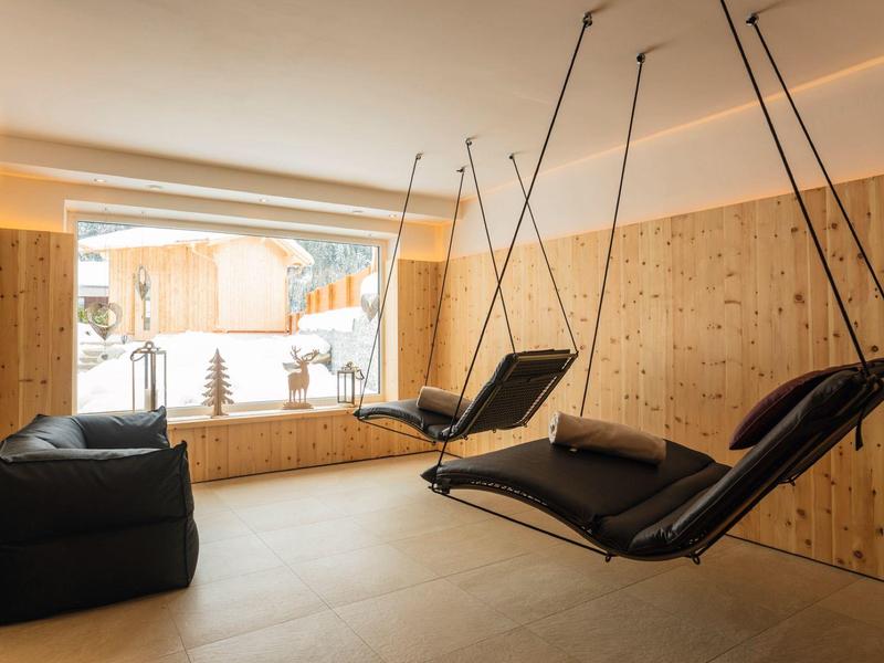 Innenraum mit Holzverkleidung, zwei schwarzen Hängesesseln und einem schwarzen Sitzsack vor großem Fenster.