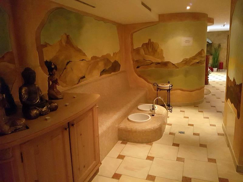 Flur mit cremefarbenem Fliesenboden, Wandmalereien und hölzernen Möbeln mit Dekoration.