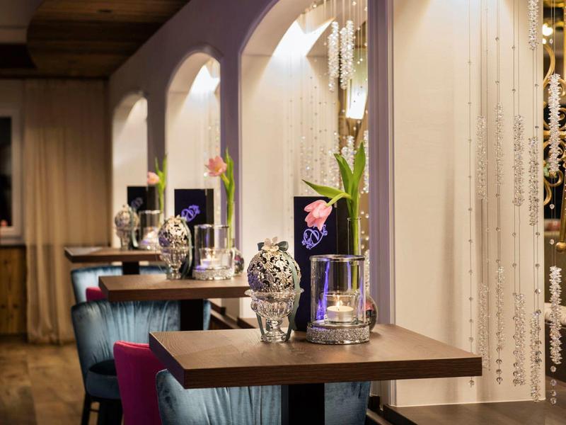 Gemütliches Restaurant mit Holz- und Stoffmöbeln, dekorativen Vasen und sanfter Beleuchtung.