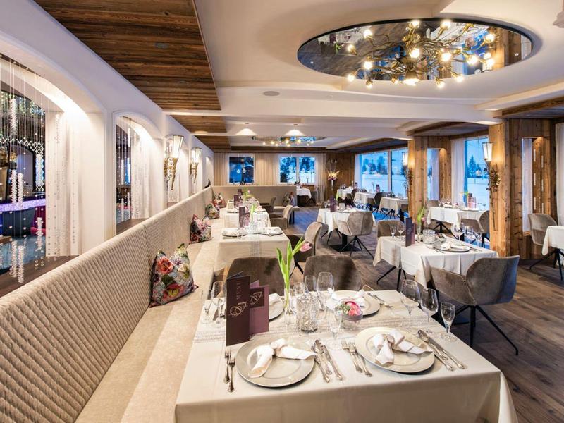 Elegantes Restaurant mit weißen gedeckten Tischen, gemütlichen Sitzbänken und großem Fensterblick.