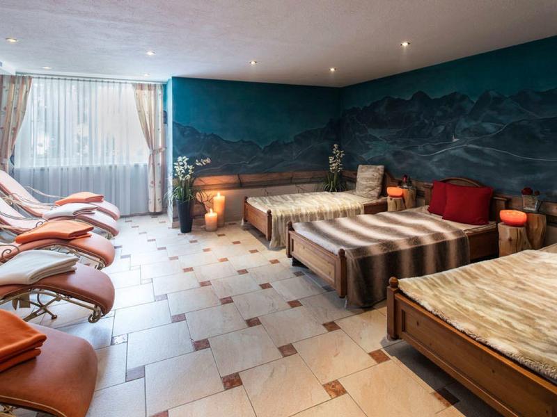 Ein heller Ruheraum mit mehreren Liegen und Betten, blau gestrichene Wände und quadratische Fliesen.