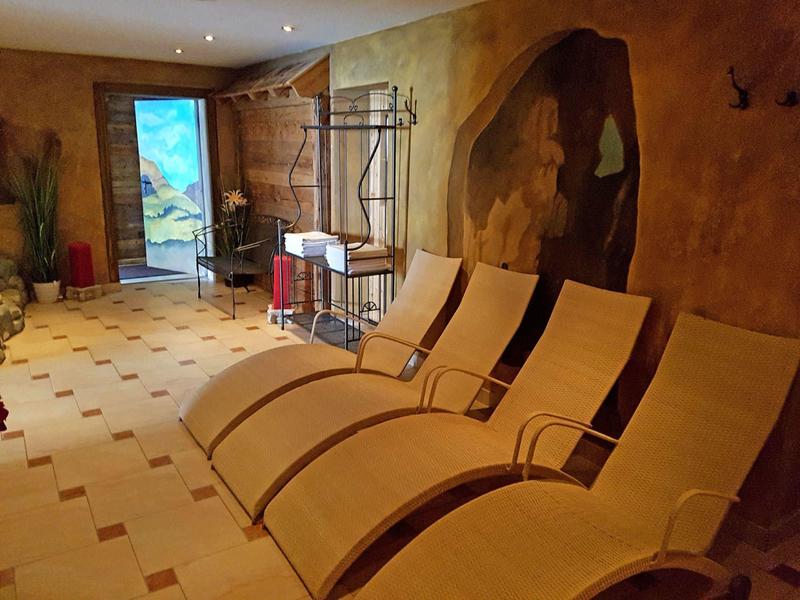 Ruheraum mit drei beigen Liegestühlen vor einer orangefarbenen Wand und großem Fenster.