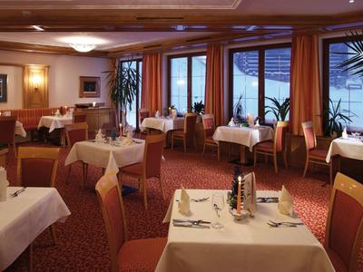 Eleganter Restaurantraum mit gedeckten Tischen, roten Teppichen und großen Fenstern zum Meerblick.