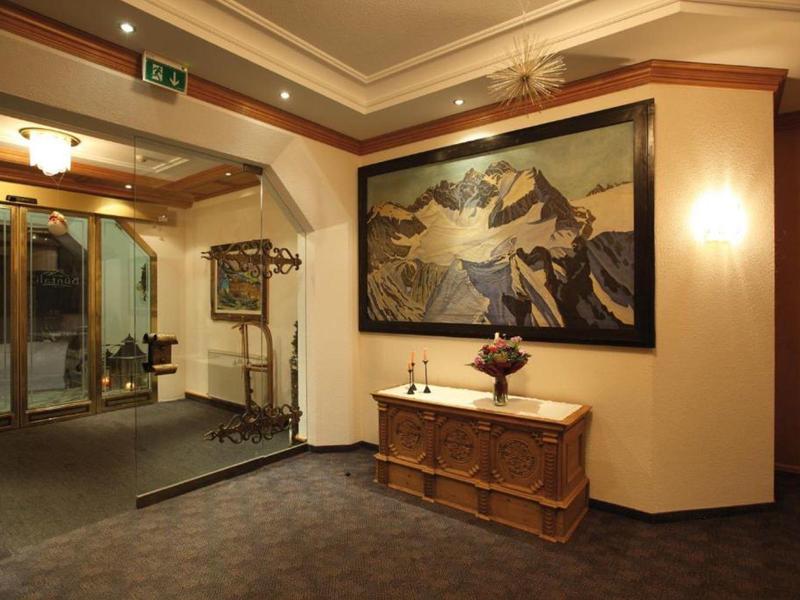 Hotel-Eingangsbereich mit Pflanzen, Gemälde, antikem Möbel und Teppichboden.