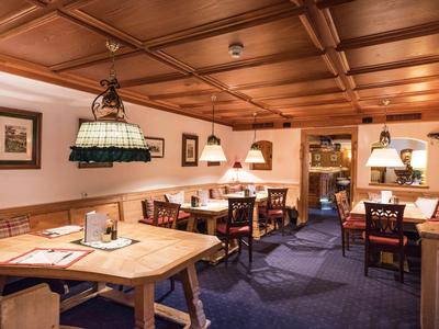 Příjemná jídelna s dřevěnými stoly, židlemi a teplým osvětlením v hotelové restauraci.