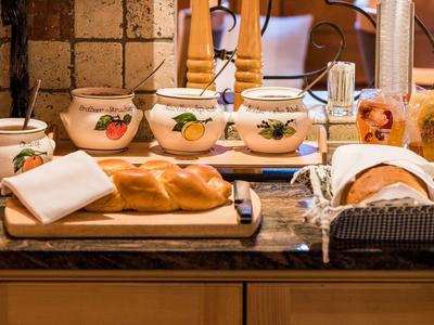 Eine Kochinsel mit vier Keramikbehältern, frischem Brot und Gewürzen auf einer Arbeitsplatte.