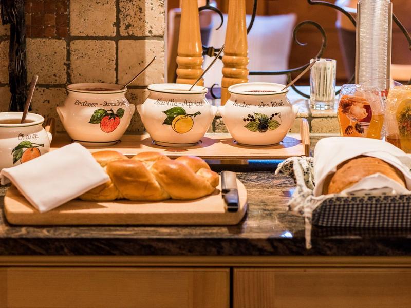 Eine Kochinsel mit vier Keramikbehältern, frischem Brot und Gewürzen auf einer Arbeitsplatte.