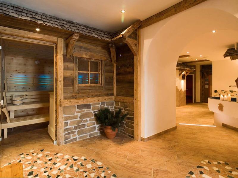 Rustikaler Flur mit Holz- und Steinwänden, sichtbaren Balken und offenem Zugang zu mehreren Räumen.