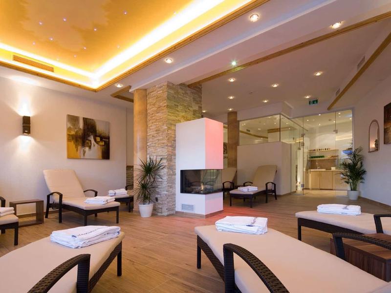 Moderner Wellnessraum mit Liegen, warmem Holzfußboden, gemauertem Kamin und indirekter Beleuchtung.