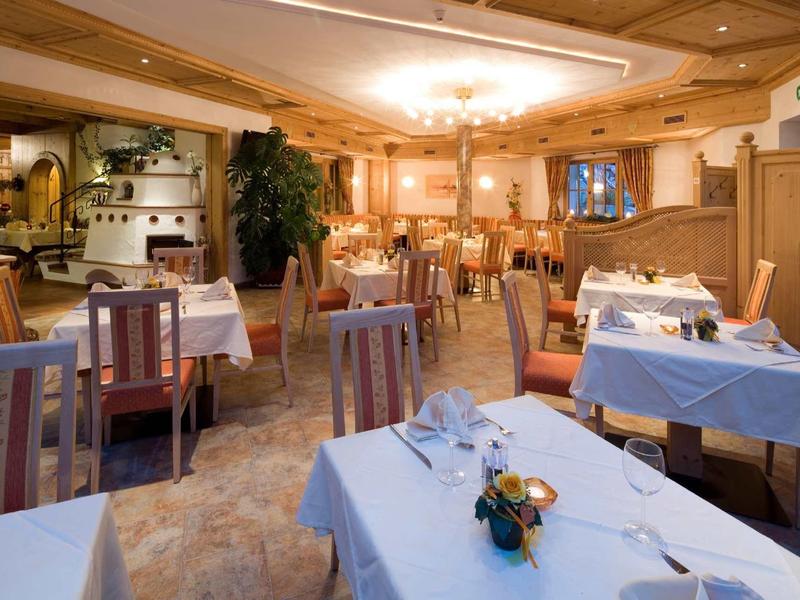 Gemütliches Restaurant mit Holzmöbeln, weißen Tischdecken und warmem Deckenlicht.