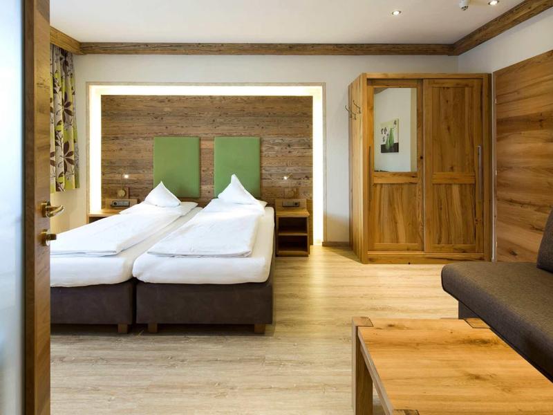 Hell eingerichtetes Schlafzimmer mit Doppelbett, Holzfußboden, Kleiderschrank und Couch.