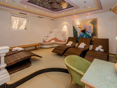 Sala relax con lettini, sedie e tavolo in un'area con illuminazione calda.