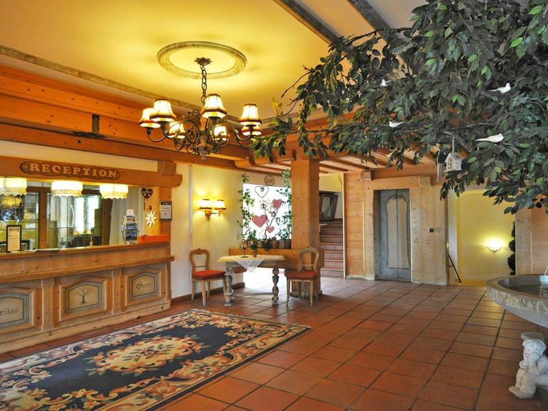 Großer Empfangsbereich mit hölzernen Balken, Teppichen, Kronleuchtern und Sitzmöbeln in warmen Farben.