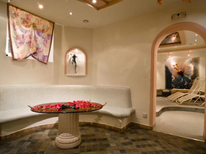 Gemütlicher Raum mit weißer Sitzbank, rundem Tisch mit Rosenblättern und weichen, warmen Farben.