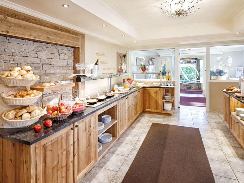 Buffet mit Brötchen, Äpfeln und verschiedenen Speisen in heller Holzküche mit Fliesenboden.