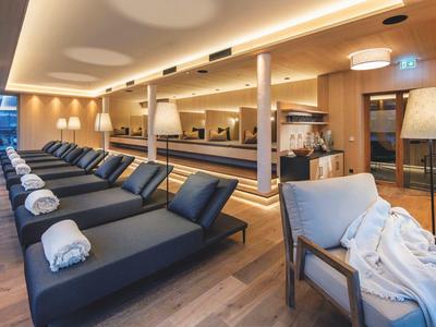 Moderner Spa-Ruheraum mit schwarzen Liegen, weißen Handtüchern und warmem Holzdekor.