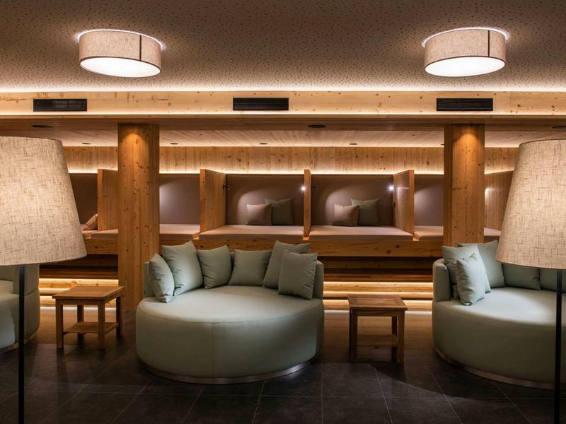 Gemütlicher Lounge-Bereich mit runden Sofas, Holzelementen und warmem, indirektem Licht.