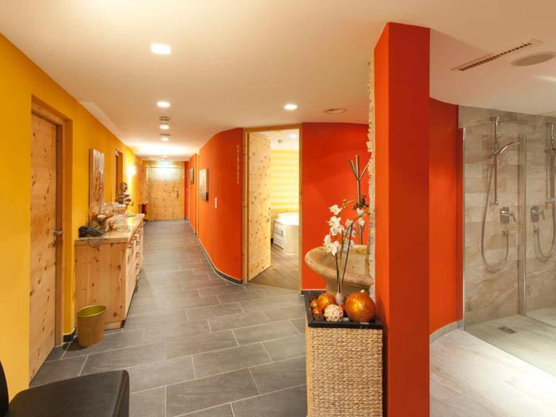 Moderner Flur mit gelben und orangen Wänden, grauem Boden und indirekter Deckenbeleuchtung.