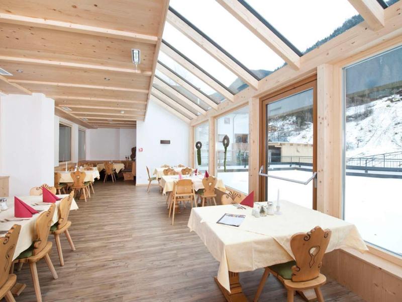 Helles Restaurant mit Holzmöbeln, Glaswand und Schneelandschaft draußen.
