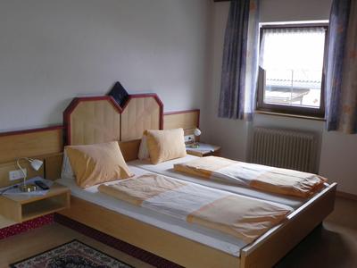 Una camera d'hotel semplicemente arredata con due letti singoli, comodini e una finestra con tende.