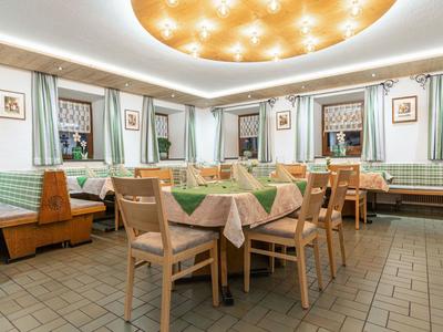 Sala da pranzo accogliente con mobili in legno, tovaglie decorative e grandi finestre.