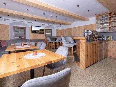 Ristorante luminoso con tavoli in legno, sedie grigie e bar moderno in un'atmosfera accogliente.