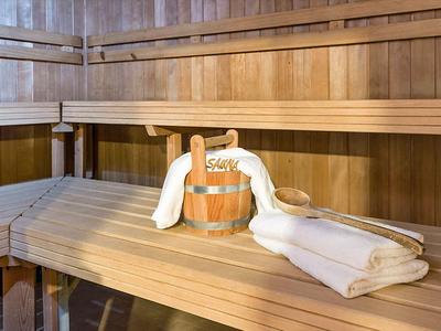 Holzsauna mit Holzbank, Saunaeimer und zwei weißen Handtüchern darauf.