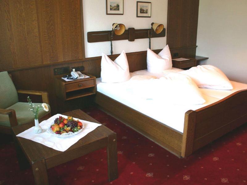 Gemütliches Schlafzimmer mit Holzmöbeln, Doppelbett, rotem Teppich und einer Sitzgruppe mit Obst.