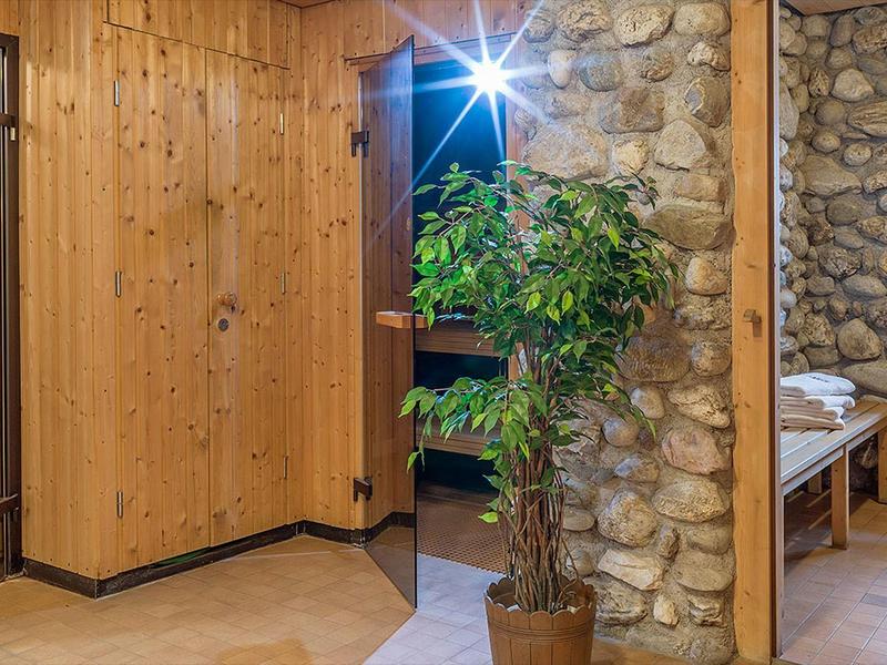 Gemütlicher Raum mit Holz- und Steinwänden, Topfpflanze und einer Sitzbank neben einem Fenster.