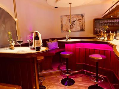 Gemütliche Bar mit Holzvertäfelung, roten Barhockern und atmosphärischer Beleuchtung.