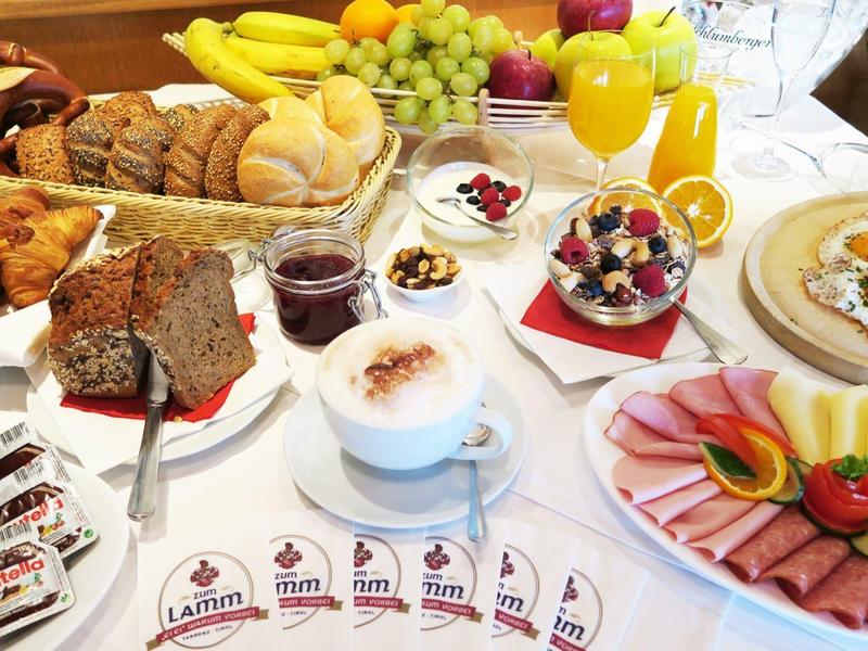 Tisch mit vielfältigem Frühstück: Gebäck, Obst, Aufschnitt, Marmeladen, Kaffee und Orangensaft.