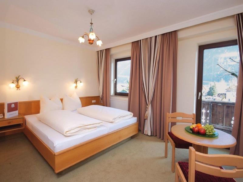 Helles Schlafzimmer mit Doppelbett, Holzmöbeln, Tisch mit Früchten und Blick auf Berge durch Fenster.