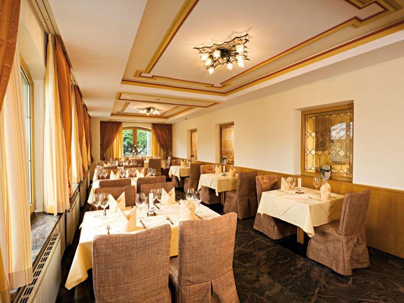 Heller, rechteckiger Speisesaal mit gedeckten Tischen, braunen Stühlen und großen Fenstern links.