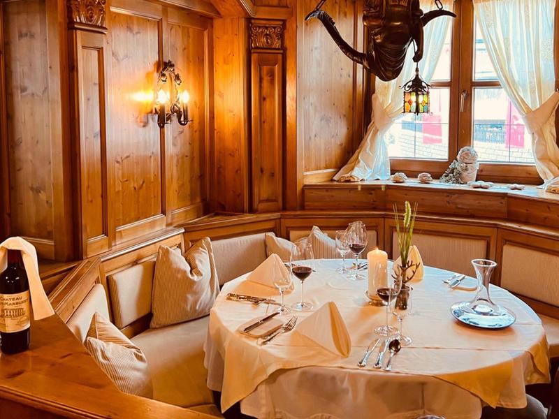 Gemütliche rustikale Sitzecke mit rundem Tisch, Tischdecke, weißen Servietten und Holzwänden.