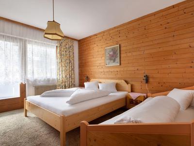 Przytulny pokój hotelowy z drewnianymi ścianami, dwoma łóżkami, zasłonami i wykładziną.