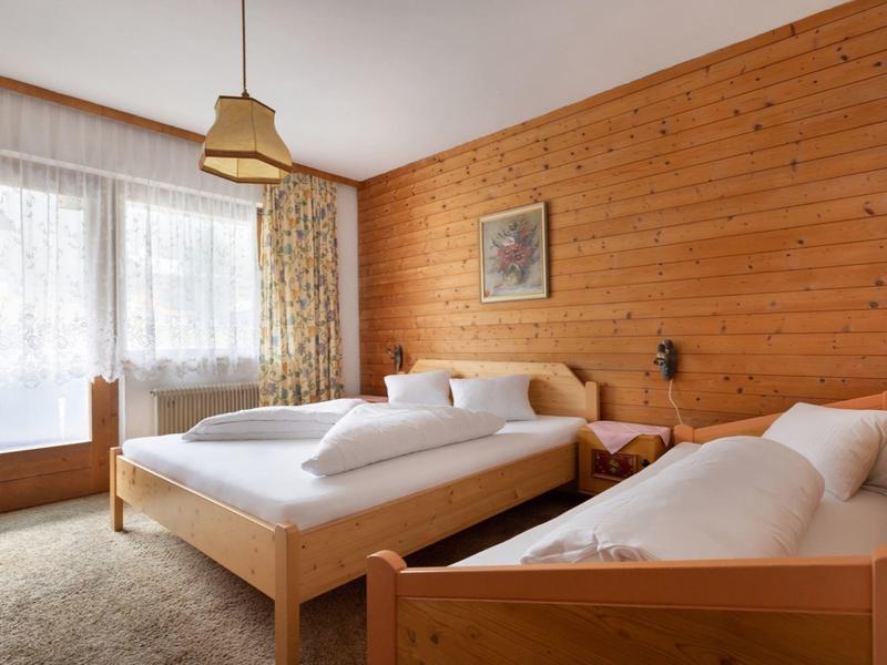 Hell eingerichtetes Schlafzimmer mit Holzwänden, zwei Betten und großen Fenstern.