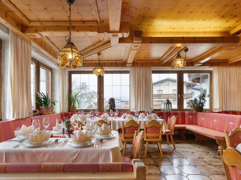 Gemütliches Restaurant mit Holzbalken, roten Sitzbänken und hellen Tischen, Fenster mit Ausblick.