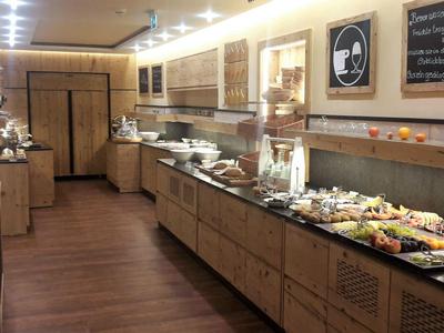 Buffet mit vielfältigen Speisen auf langen Holztresen und warmem, hellem Ambiente.