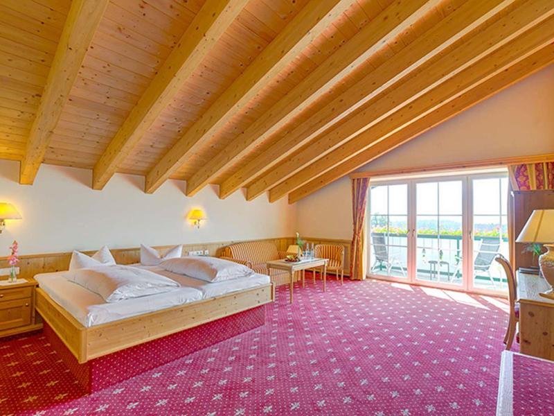 Großes Schlafzimmer mit Holzbalkendecke, Doppelbett, rotem Teppich und bodentiefen Fenstern.