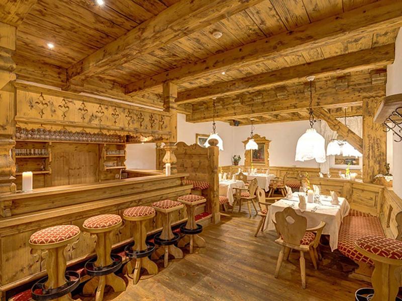 Gemütliches Restaurant mit Holzdecke, rustikalem Tresen und gepolsterten Barhockern.