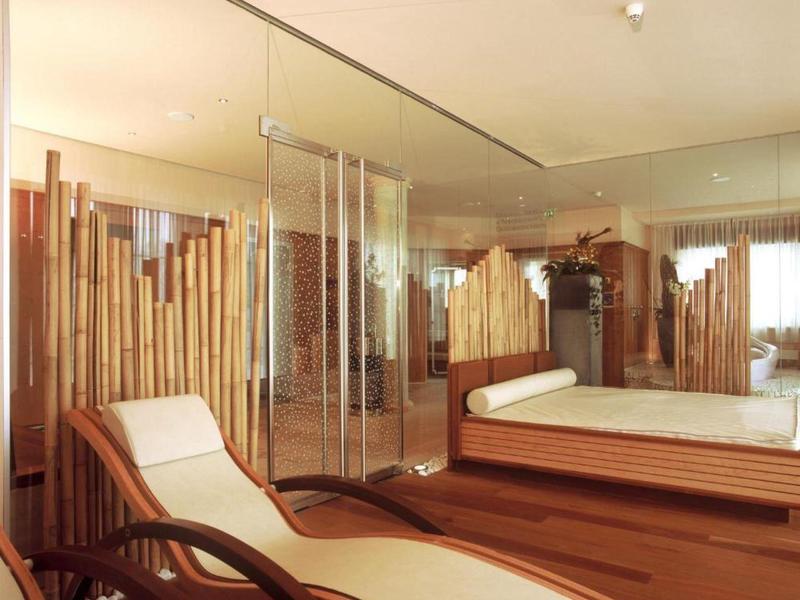 Moderner Raum mit Holzpaneelen, Glaswand, Liegestuhl und Bett mit weißer Bettwäsche.